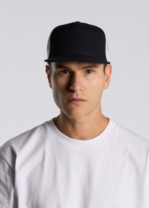 Portrait of a man wearing a black baseball cap and white T‑shirt, looking straight at the camera against a light gray background.