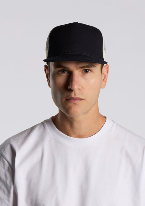 Portrait of a man wearing a black baseball cap and white T‑shirt, looking straight at the camera against a light gray background.