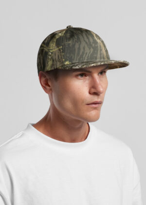 Man wearing a woodland camouflage baseball cap and white shirt, looking to the right against a gray backdrop.