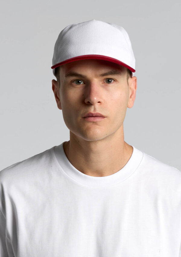 Man wearing a white cap with a red brim and a white shirt against a light gray background, facing forward.