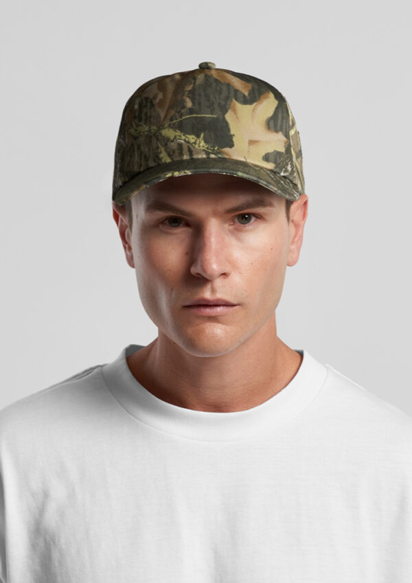 Man wearing a woodland camouflage baseball cap and a white crewneck T-shirt, facing the camera.