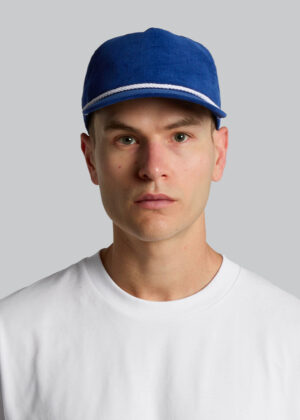 Portrait of a man wearing a blue cap with white trim and a white shirt, facing the camera against a gray background.