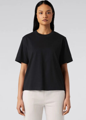 Front view of a model wearing a black short-sleeve crew-neck T-shirt and light beige pants against a neutral gray background.