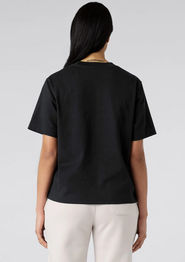 Back view of a person wearing a black short-sleeve T-shirt and light beige pants; long dark hair partially covers the neck.