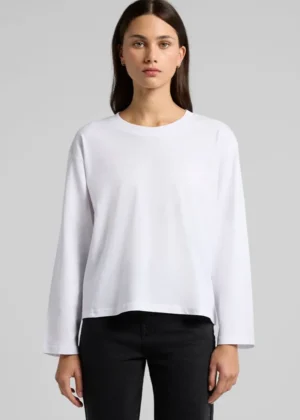 Model wearing a plain white long-sleeve shirt with a relaxed fit, paired with black pants, neutral studio backdrop
