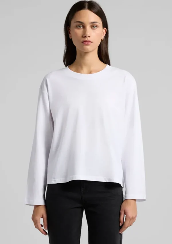 Model wearing a plain white long-sleeve shirt with a relaxed fit, paired with black pants, neutral studio backdrop