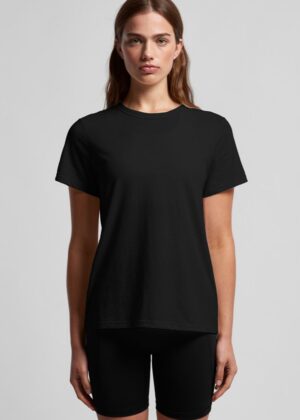 Woman in a plain black T-shirt and black shorts, standing against a light gray studio background.