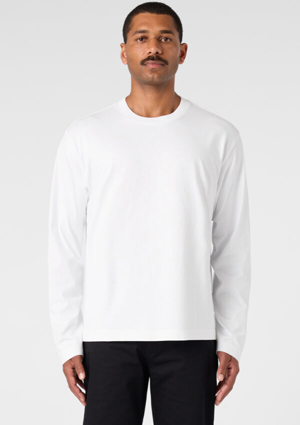 Man wearing a plain white long-sleeve crewneck shirt, standing against a light gray backdrop.