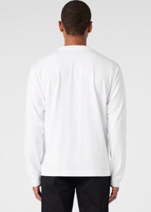 Back view of a person wearing a plain white long-sleeve shirt and black pants against a light gray background.