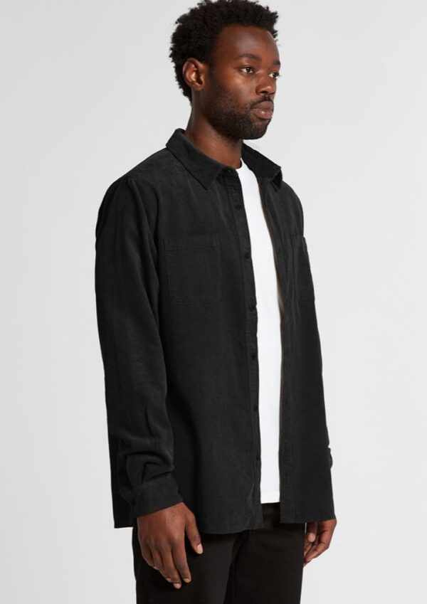 Man modeling a black long-sleeve button-up shirt over a white T-shirt against a light gray studio background.
