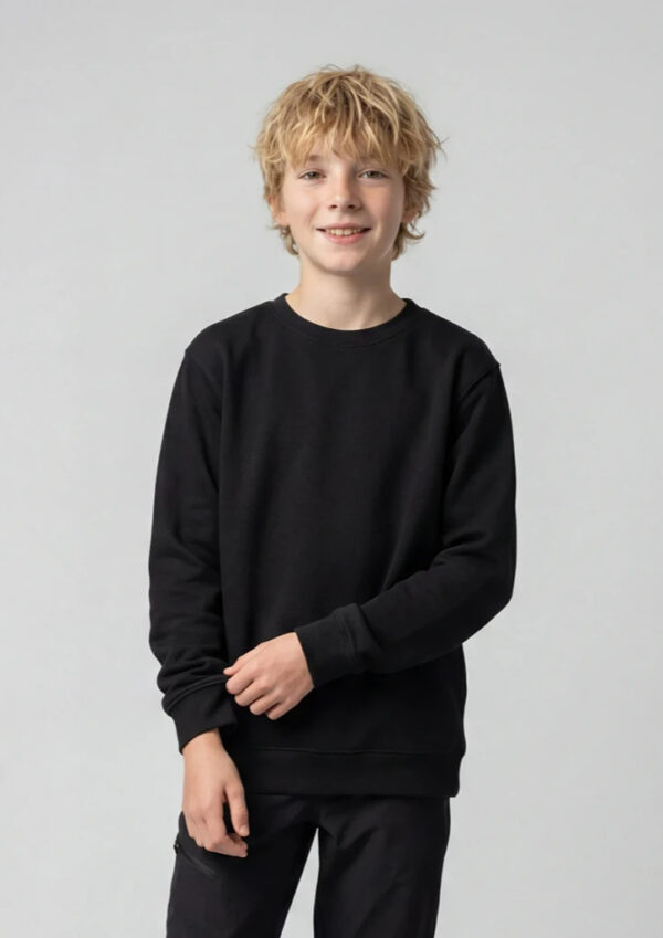A smiling boy with blond hair wearing a black sweatshirt and black pants against a light gray background.