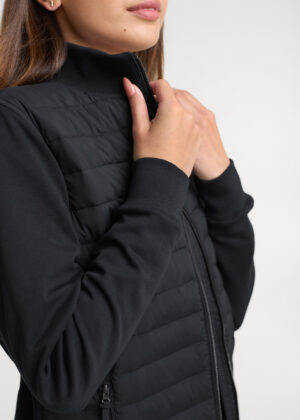 Close-up of a person zipping up a black quilted jacket at the collar with both hands