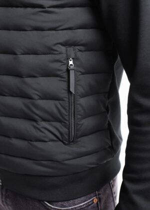 Close-up of a black puffer jacket with a vertical zippered pocket on the side, showing the zipper pull and stitching detail