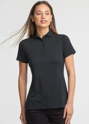 Woman wearing a black polo shirt with short sleeves and a button placket, standing against a light background.”,