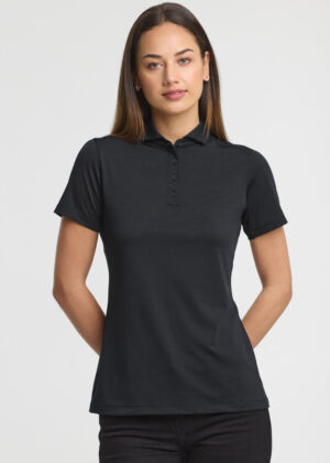 Model wearing a dark gray polo shirt with buttons, standing against a light background, hands behind her back.