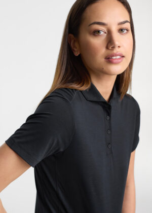 Portrait of a woman wearing a black polo shirt against a light gray background.