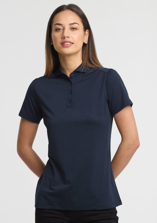 Woman modeling a navy polo shirt with short sleeves and button placket, standing against a light background.