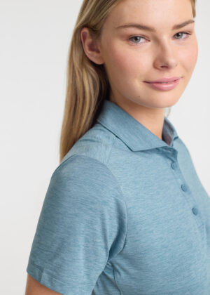 Portrait of a young woman with blonde hair wearing a light blue polo shirt, facing slightly to the side with a soft smile.