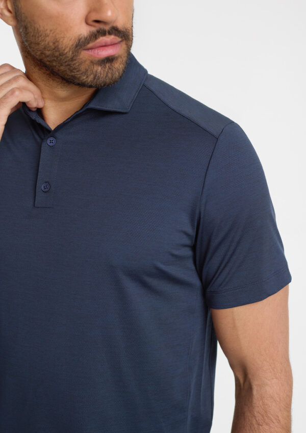Man wearing a navy polo shirt, close-up of upper torso and face turned slightly to the left.