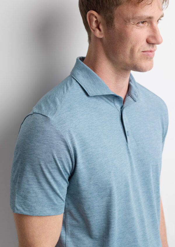 Side view of a man wearing a light blue polo shirt with a collar, short sleeves, and a subtle heathered texture.