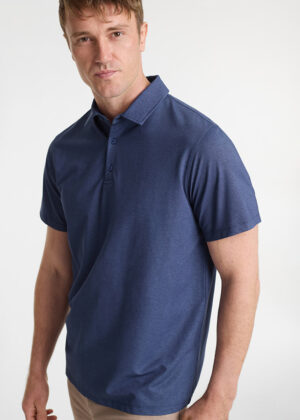 Male model wearing a navy blue polo shirt, standing against a light background, facing slightly to the left.