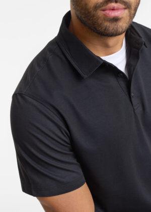 Close-up of a man wearing a black polo shirt, showing the collar and short sleeves with a white undershirt at the neck.