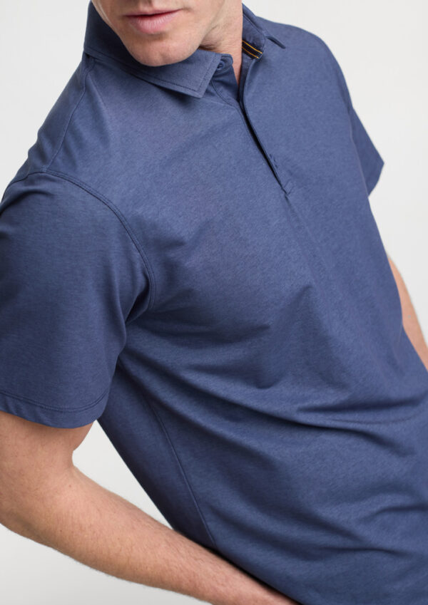 Man wearing a navy polo shirt from the chest up, showing collar and short sleeves in a studio shot