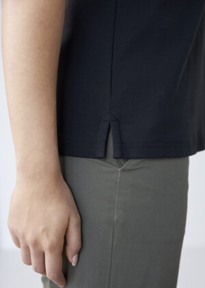 Close-up of navy shirt hem with a small side slit over olive pants, highlighting the garment detail.
