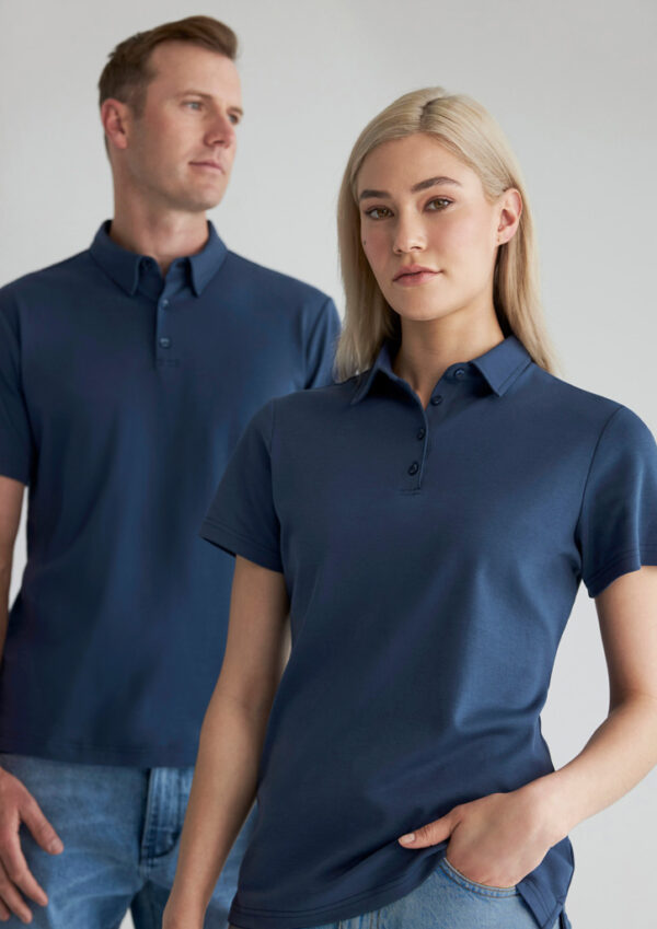 Two models wear navy polo shirts; woman in front, man in the background.