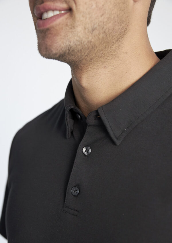 Close-up of a man's lower face with light stubble wearing a black polo shirt with a buttoned placket.