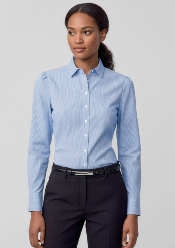 fbs812ll_worn_00 Woman wearing a light blue striped button-down shirt and black dress pants, standing against a light gray background.