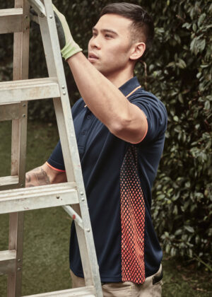 Man in a navy polo with orange trim stabilizes a metal ladder outdoors in a garden.