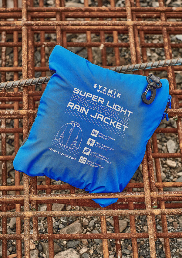 Bright blue packable rain jacket pouch with white text and icons, laid on a rusted metal grid.