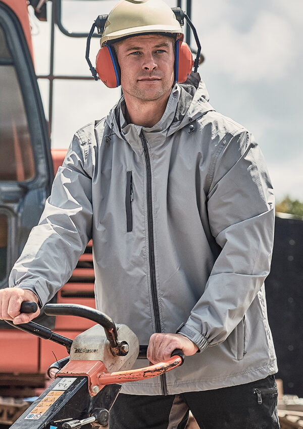 Construction worker wearing a hard hat and orange ear protection operating a walk-behind compactor outdoors