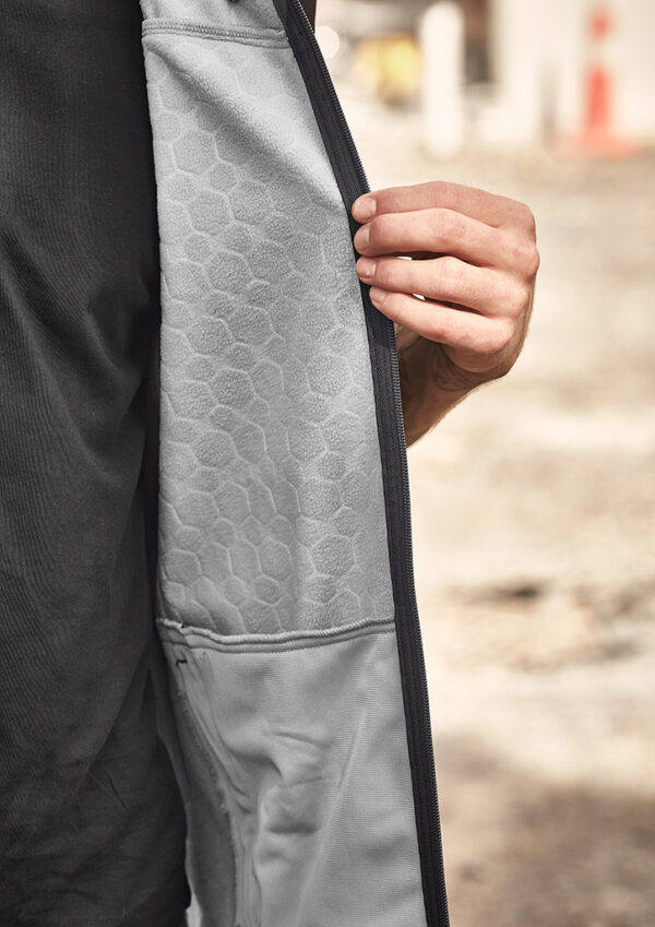 Close-up of a person unzipping a light gray jacket, revealing a hexagonal-patterned lining.