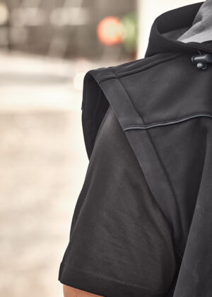 Close-up of a black hooded jacket from the shoulder, showing the sleeve and hood drawstring outdoors.