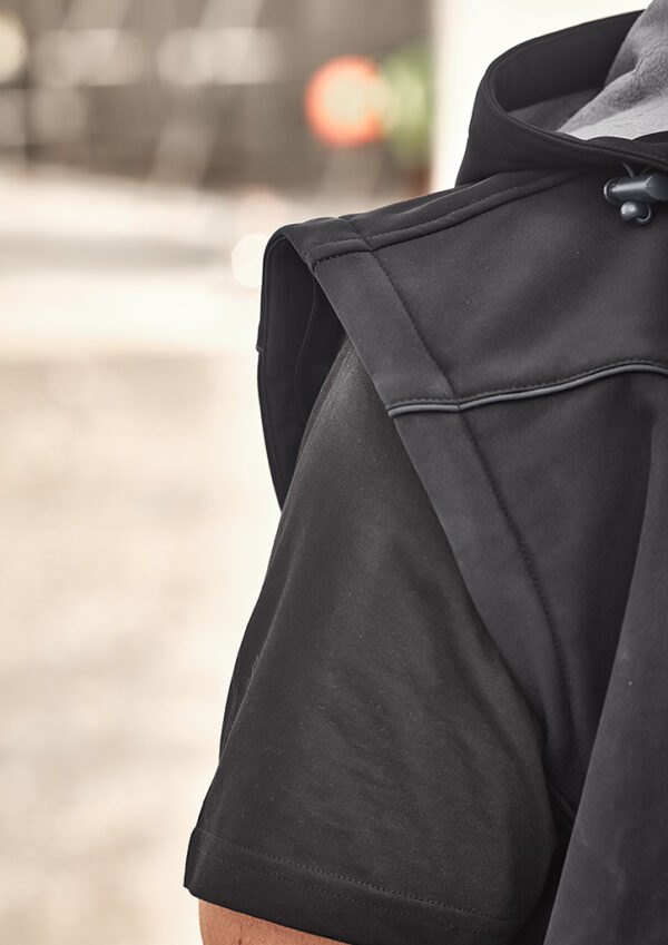 Close-up of a black hooded jacket from the shoulder, showing the sleeve and hood drawstring outdoors.