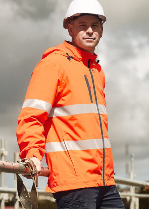 Construction worker in a bright orange high-visibility jacket and white hard hat leaning on a railing outdoors.