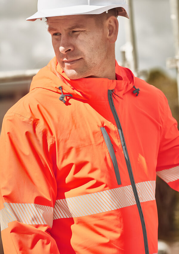 Construction worker in a bright orange safety jacket with reflective stripes and a white hard hat, looking to the side.