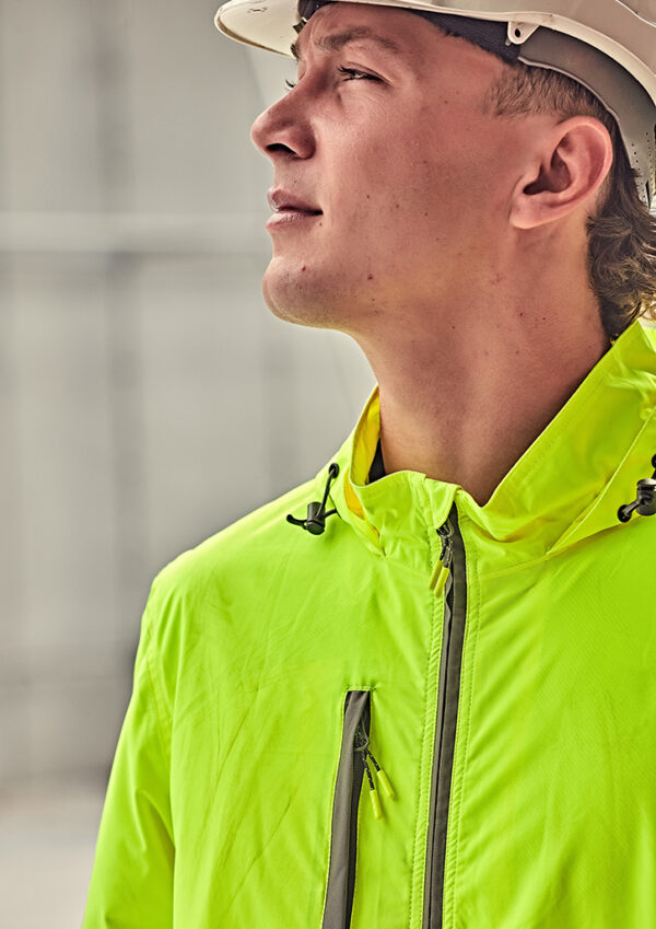 Construction worker in a neon yellow jacket and hard hat looks upward in profile view, outdoors.