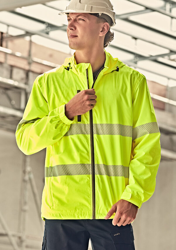 Construction worker in a neon yellow high-visibility jacket and white hard hat, looking to the left at a construction site.