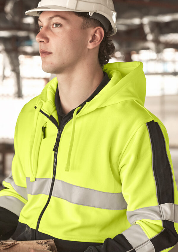 Construction worker in a neon safety jacket and white hard hat, looking to the left in an industrial setting