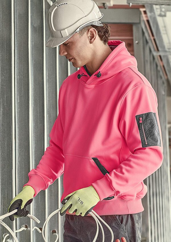 Construction worker in a pink hoodie and hard hat handling white electrical cables at a construction site