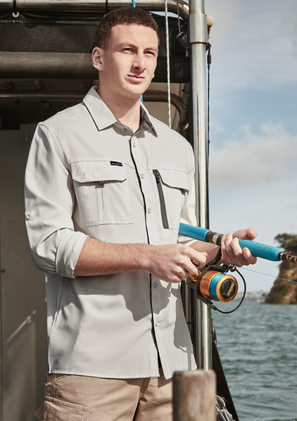 Man on a boat fishing, holding a blue fishing rod with a spinning reel by the water.