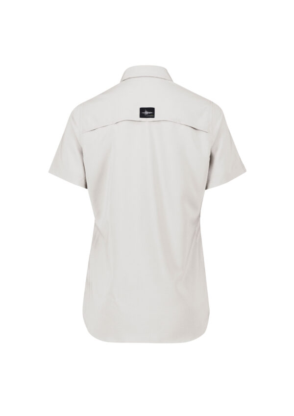 Back view of a light beige short-sleeve shirt with a small black brand patch on the upper back center.